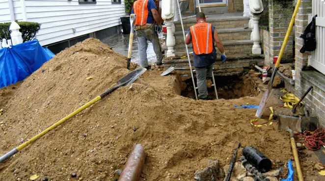 Contractors performing foundation protection and exterior drainage excavation near residential home steps in Myrtle Beach, SC
