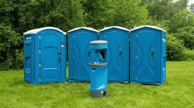 Four blue portable toilets and a matching hand washing station on grass near trees, a common sight at local outdoor events in Myrtle Beach, SC
